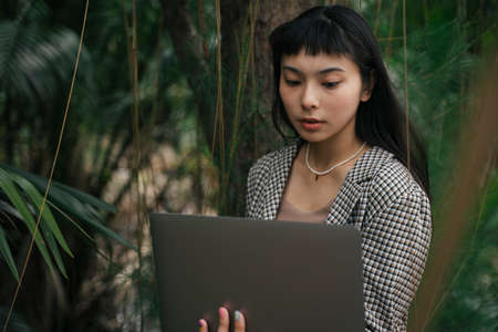 Asian business woman in formal shirt using computer laptop outdoors.