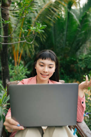 Asian business woman in formal shirt using laptop in nature outdoors.