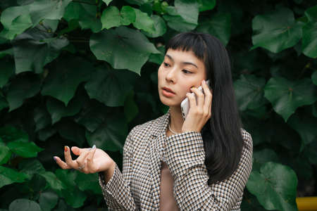 Asian business woman in formal shirt using smartphone on nature background.の写真素材
