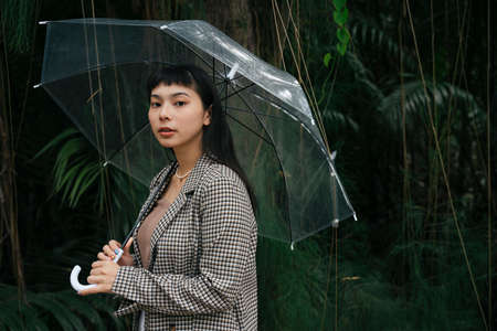 Fashion portrait of asian business woman in formal shirt holding transparent umbrella.の写真素材
