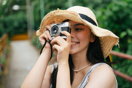 Fashion portrait of young asian woman with vintage camera. Beautiful photographer at resort.