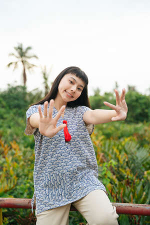 Portrait of beautfiul asian dark hair showing two hands at country side.の写真素材