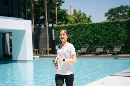 Healthy asian woman running or jogging near swimming pool.