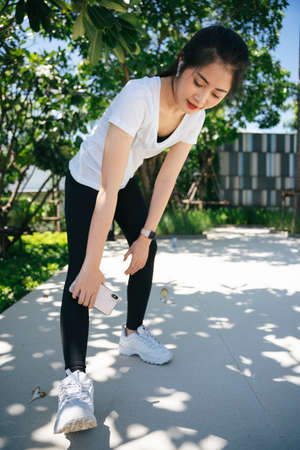 Portrait of healthy asian woman in white shirt warm up before work out at park.
