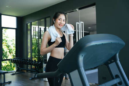 Healthy asian woman running on treadmill machine in gym.の写真素材