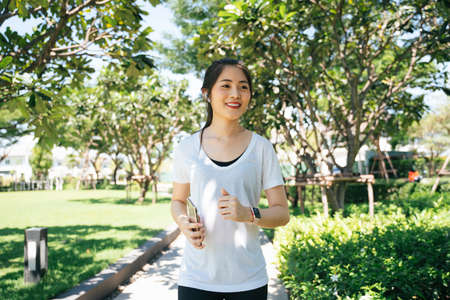 Sporty asian woman running or jogging on a path at park in summer season.の写真素材