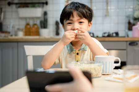 Boy eating dinner and watching video on tablet.の写真素材