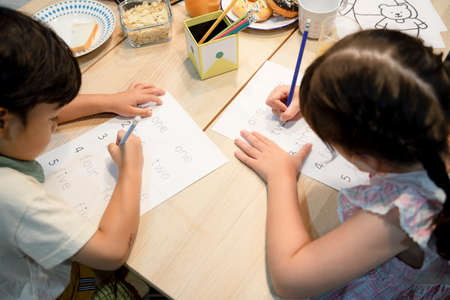 Sister and brother helping each other do homework together at home.
