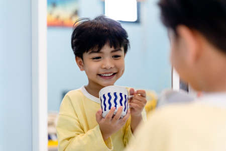 Little boy having breakfast with fresh milk infront of the mirror.の写真素材