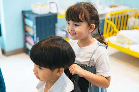 Cute sister helping her brother dress up formal suit at bedroom.の写真素材