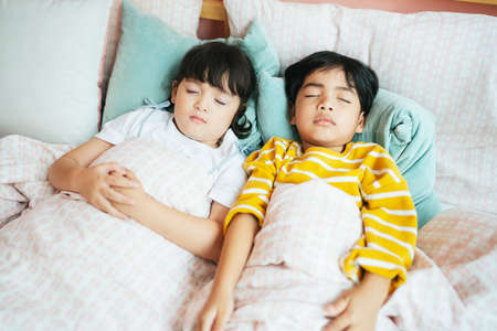 Top view - Sister and brother sleeping on the bed together.の写真素材
