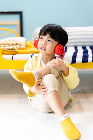 Little boy enjoy listen to music with wireless headphone at bedroom.の写真素材