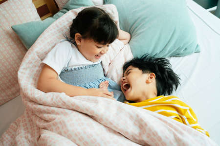 Top view - Brother and sister having fun and relaxing on bed.の写真素材
