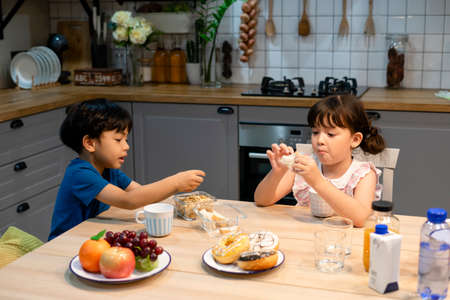 Siblings having breakfast in kitchen before going to school.の写真素材