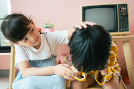 Little sister try to soothe her tearful brother by pating the head.の写真素材