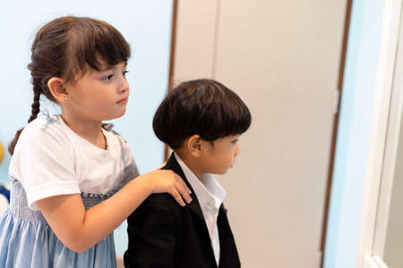 Sister helping her brother dress up formal suit in wardrobe room at home.の写真素材