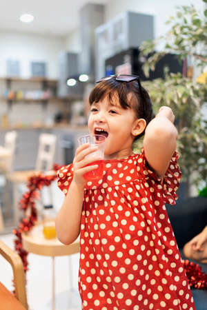 Little girl in red dress enjoy christmas the party at home.