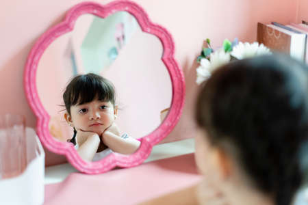 Bored girl looking at the mirror in bedroom.の写真素材