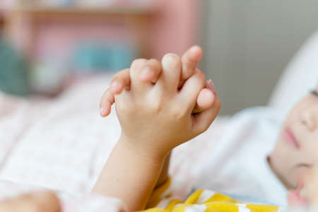 Close up hands of two kids holding hands while sleeping.