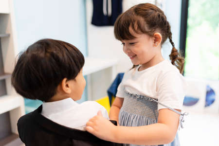 Sister helping her brother dress up formal suit in wardrobe room at home.の写真素材