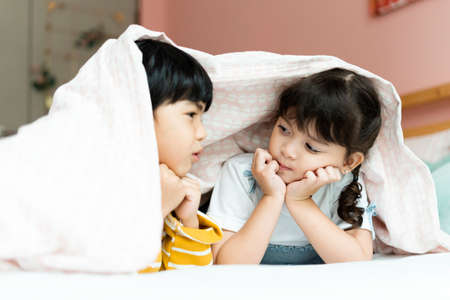 Boy and girl having fun stay under blanket in bedroom.の写真素材