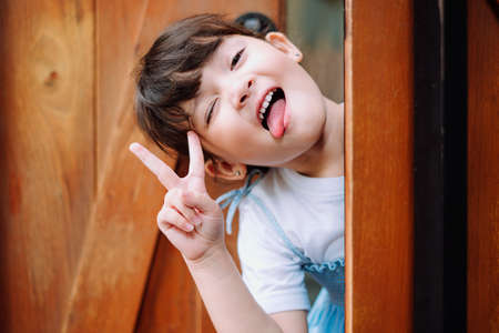 Close up portrait of little girl with cheerful expression at wooden barn doors.の写真素材