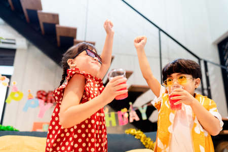 Sister and brother raise their hands up in the air having fun in the party.の写真素材