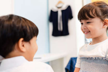 Sister helping her brother dress up formal suit in wardrobe room at home.の写真素材