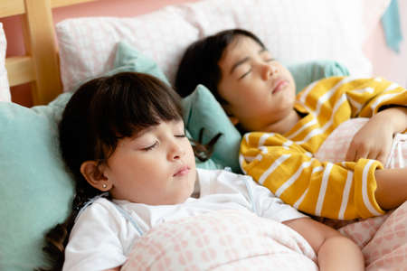 Sister and brother sleeping together in bedroom.の写真素材