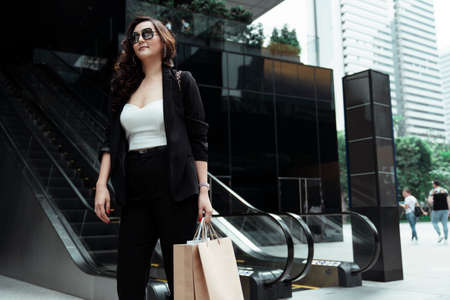 Formal asian businesswoman wearing sunglasses holding paper bags - Shopping concepts.の写真素材