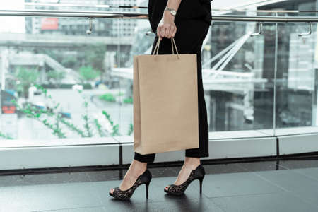 Hand of woman holding shopping bag, standing on high heel - shopping concept.の写真素材
