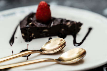 Two golden spoons on chocolate cake plate at cafe.の写真素材