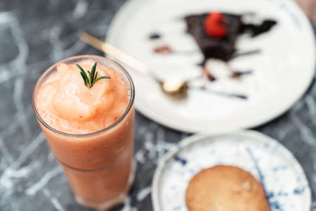 Close up shot - Thai tea milk shake in glass cup and chocolate cake also crispy cookie on white...