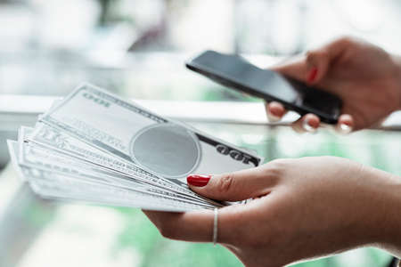 Hand of woman holding cash banknote online shopping on smartphone.の写真素材