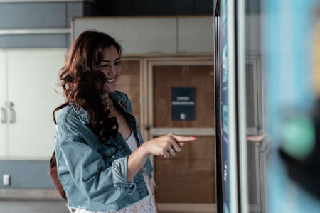 Cheerful asian woman pointing at board, reading city map, traveling in the city. Copy space....