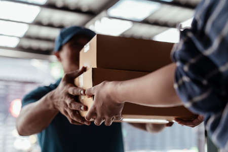 Local delivery worker on duty delivering cardboard boxes to customer to their house.の写真素材