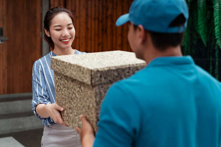 Asian woman hand accepting a delivery of boxes from deliveryman on blue costume.の写真素材
