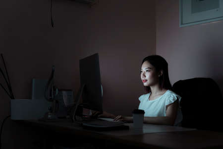 Asian businesswoman working in the office room infront of computer until midnight - Over time working concept.の写真素材