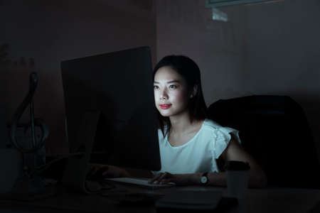 Asian businesswoman working in the office room infront of computer until midnight - Over time working concept.の写真素材