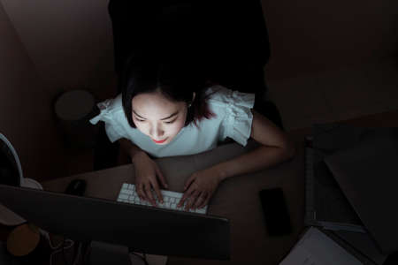Top view - Asian businesswoman working on computer until midnight in office room.の写真素材
