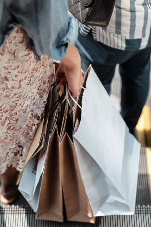 Close hands of woman holding shopping paper bags walking down stair.の写真素材