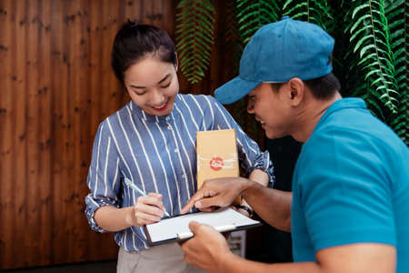 Woman signing on receipt paper to get her packages.の写真素材