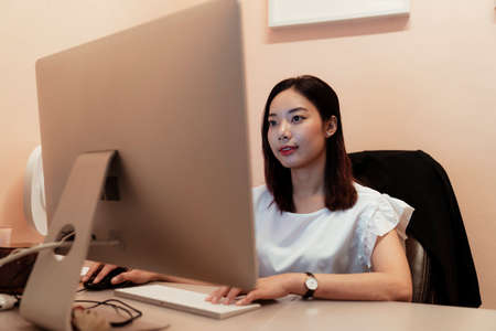 Asian thai beautiful woman chatting on computer in office room. Working in the office alone. Boss and manager.の写真素材