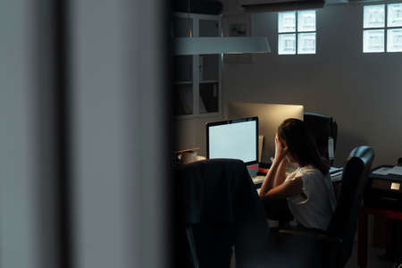 Thai asian mature and tired businesswoman working on computer until night.の写真素材