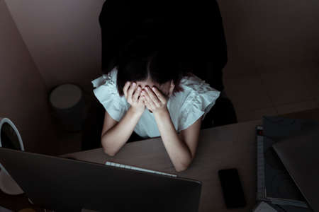 Stressful asian businesswoman working in the office infront of computer until midnight. Unhealthy condition. Migraine and Headache.の写真素材