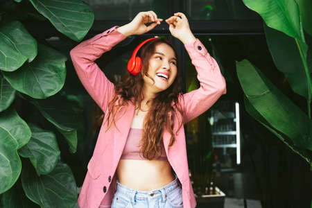 Portrait of asian young woman enjoy listen to music with headphone and dancing with fun expression.の写真素材