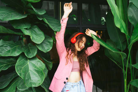 Portrait of asian young woman enjoy listen to music with headphone and dancing with fun expression.の写真素材