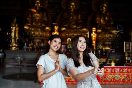 Two young thai girls doing vlog with action camera stick about Thai traditional in a temple.の写真素材