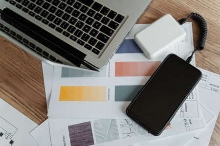 Cropped image of smartphone on the table connect with powerbank for charging on the prototype of art next to the laptop.の写真素材