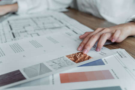Cropped image of woman's hand point her fingers on the example of texture on the paper while she choose for the building.の写真素材
